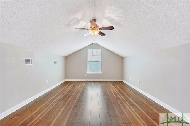 additional living space featuring ceiling fan, a textured ceiling, lofted ceiling, and hardwood / wood-style floors