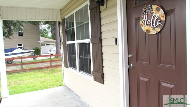 doorway to property featuring a yard, a porch, and a garage