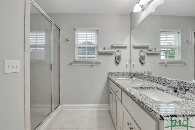 bathroom with tile patterned flooring, a shower with door, vanity, and a wealth of natural light