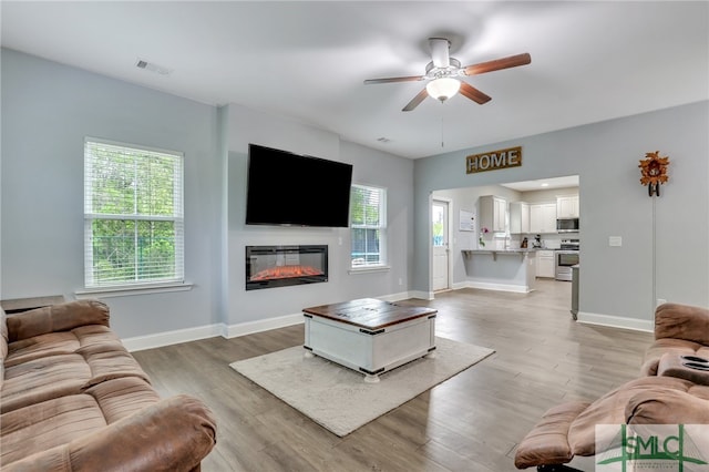 living room with light wood-type flooring and ceiling fan