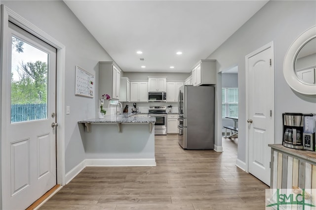 kitchen with light hardwood / wood-style flooring, white cabinetry, appliances with stainless steel finishes, and plenty of natural light