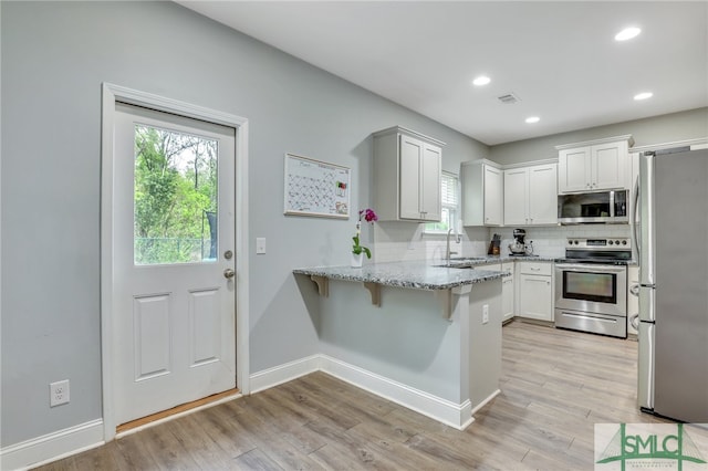 kitchen with light hardwood / wood-style floors, sink, stainless steel appliances, and white cabinets