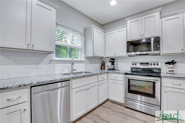 kitchen featuring light hardwood / wood-style floors, tasteful backsplash, sink, white cabinets, and appliances with stainless steel finishes