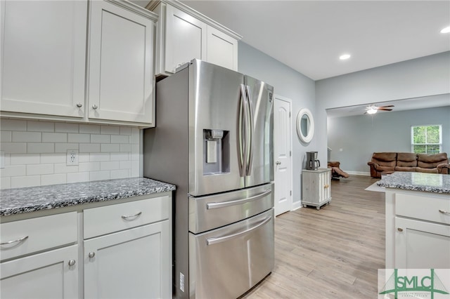 kitchen with ceiling fan, stainless steel fridge, white cabinetry, light hardwood / wood-style floors, and decorative backsplash