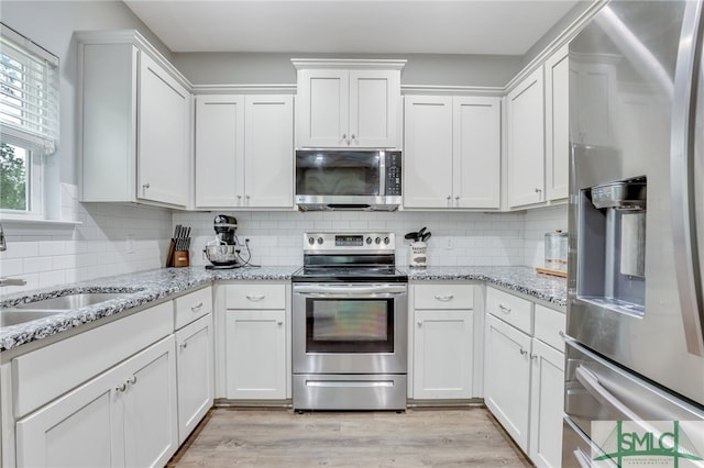 kitchen with white cabinetry, light hardwood / wood-style flooring, stainless steel appliances, and tasteful backsplash