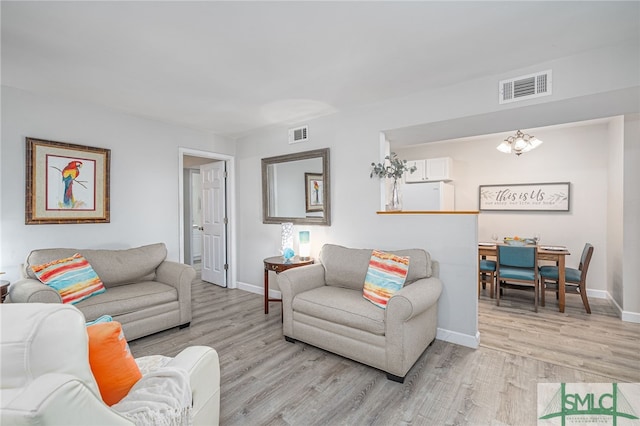 living area featuring light wood-style flooring, baseboards, and visible vents