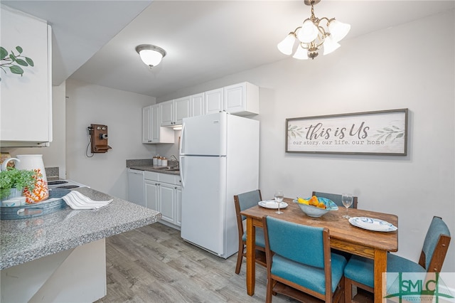 kitchen with an inviting chandelier, light hardwood / wood-style floors, white appliances, and white cabinetry