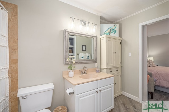 bathroom featuring wood-type flooring, ornamental molding, vanity, and toilet