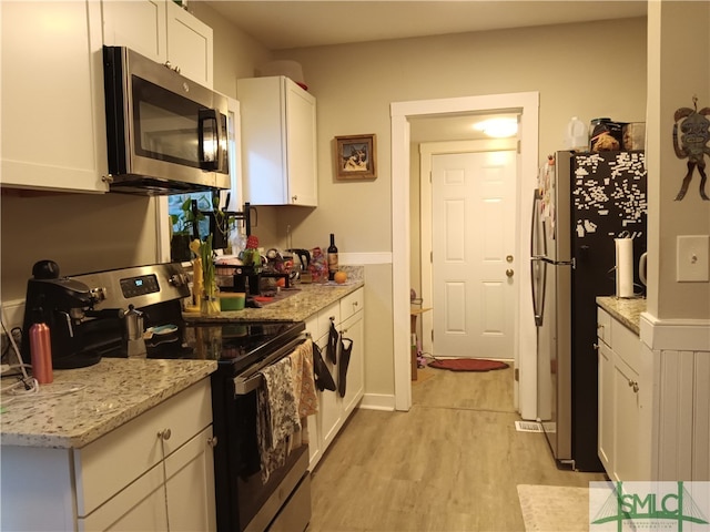 kitchen featuring appliances with stainless steel finishes, light hardwood / wood-style floors, white cabinetry, and light stone countertops