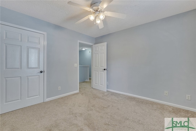 unfurnished bedroom featuring a textured ceiling, ceiling fan, and light colored carpet