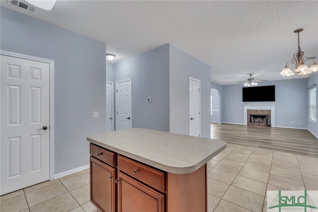 kitchen featuring a kitchen island, a textured ceiling, light hardwood / wood-style flooring, decorative light fixtures, and ceiling fan with notable chandelier