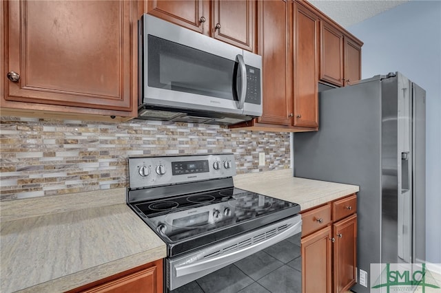 kitchen with a textured ceiling, decorative backsplash, tile patterned flooring, and stainless steel appliances