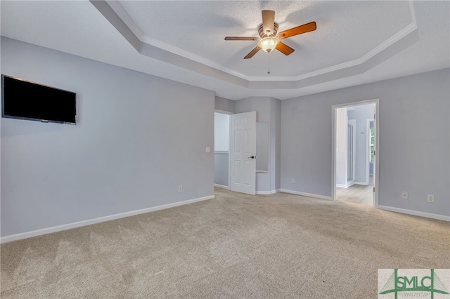 carpeted empty room featuring ceiling fan, a tray ceiling, and crown molding