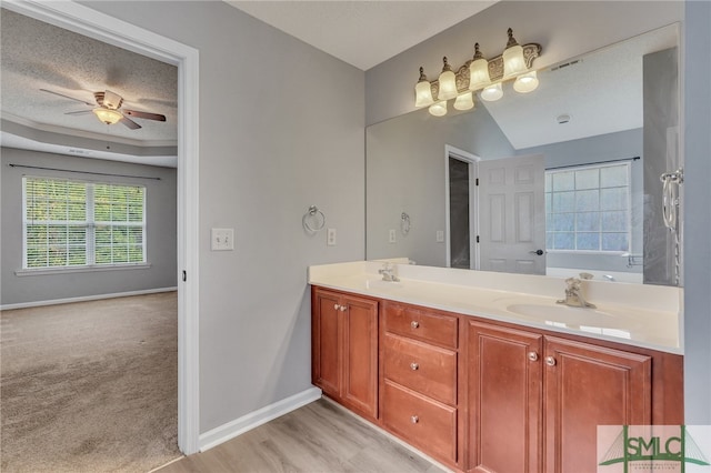 bathroom with a textured ceiling, wood-type flooring, vanity, and ceiling fan