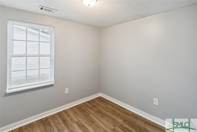 unfurnished room featuring a textured ceiling and dark hardwood / wood-style floors