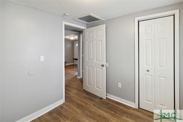 unfurnished bedroom with a textured ceiling, dark wood-type flooring, and a closet