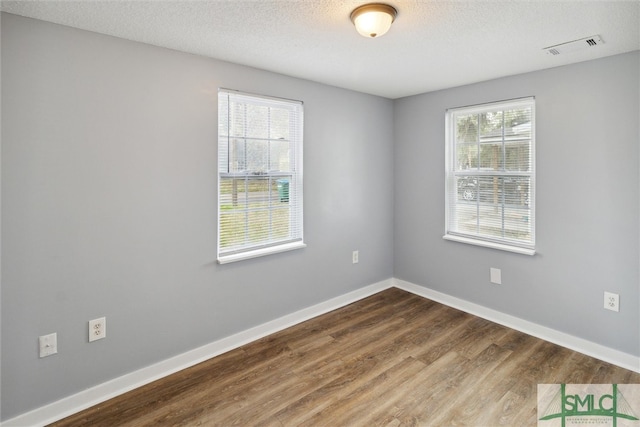 unfurnished room with hardwood / wood-style flooring, a textured ceiling, and a healthy amount of sunlight