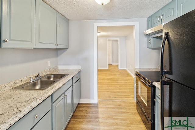 kitchen with a textured ceiling, ventilation hood, sink, light hardwood / wood-style flooring, and black appliances