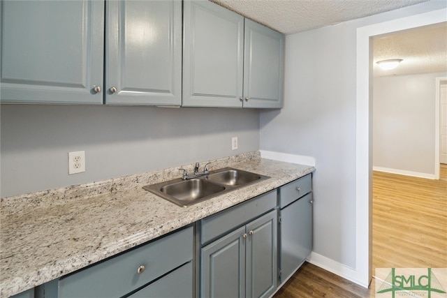 kitchen featuring a textured ceiling, gray cabinetry, sink, and dark hardwood / wood-style flooring