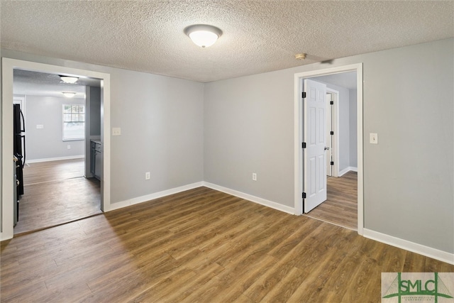 empty room featuring a textured ceiling and dark hardwood / wood-style floors