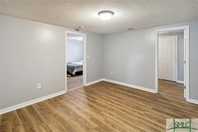 spare room featuring a textured ceiling and hardwood / wood-style floors