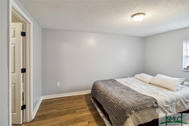 bedroom with a textured ceiling and dark hardwood / wood-style floors