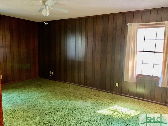 unfurnished room featuring wooden walls, ceiling fan, and carpet flooring