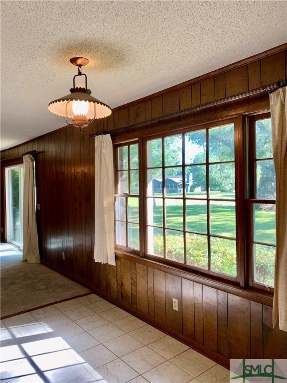 spare room with wooden walls, a textured ceiling, and light tile patterned floors