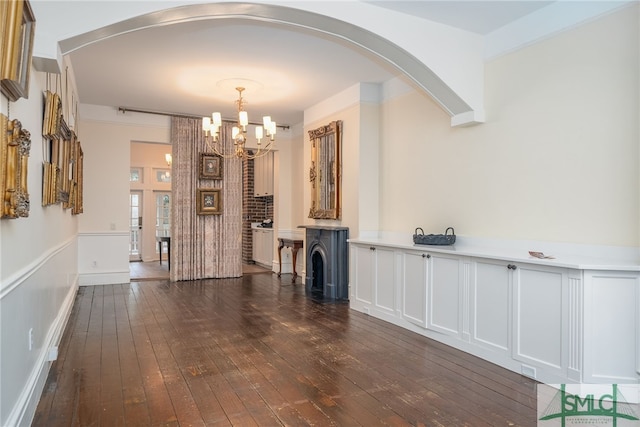 unfurnished living room with a notable chandelier and dark hardwood / wood-style floors