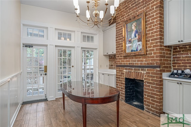 dining space with a brick fireplace, a notable chandelier, and light hardwood / wood-style floors