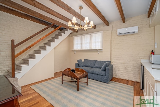 living room with beam ceiling, a wall mounted AC, brick wall, a chandelier, and light wood-type flooring