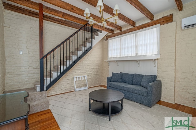 living room with brick wall, light hardwood / wood-style floors, a chandelier, and beam ceiling