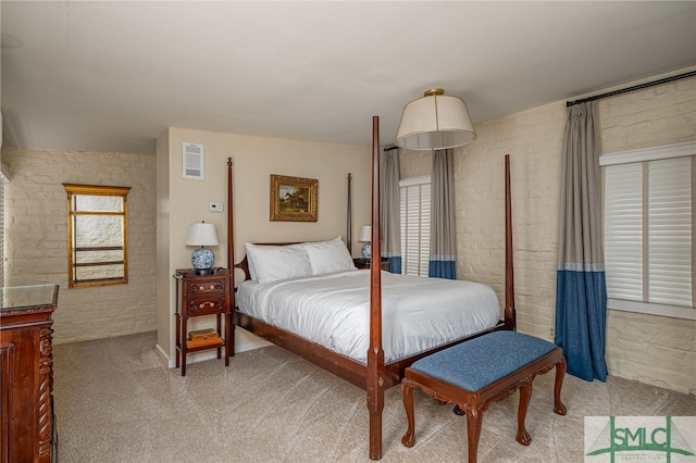 carpeted bedroom with brick wall and multiple windows