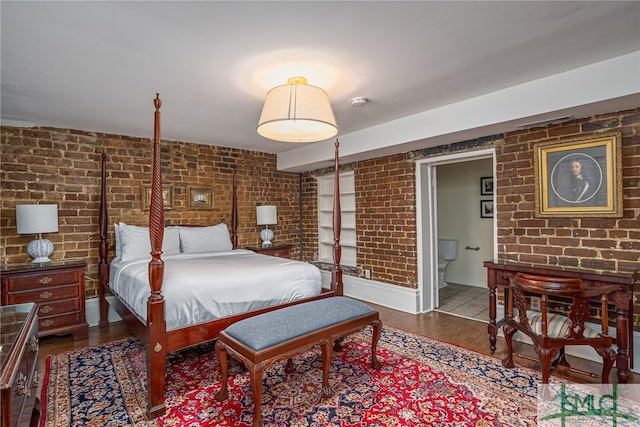 bedroom featuring hardwood / wood-style floors and brick wall