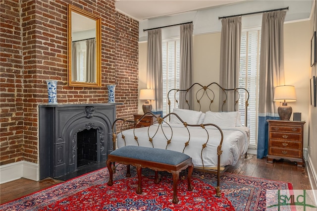 bedroom featuring multiple windows, crown molding, dark hardwood / wood-style floors, and brick wall