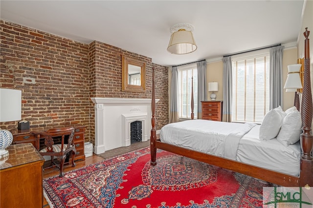 bedroom featuring hardwood / wood-style flooring and brick wall