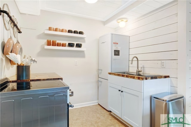 kitchen with electric range oven, wood ceiling, wooden walls, white refrigerator, and white cabinetry