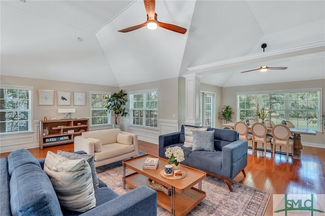 living room featuring vaulted ceiling, hardwood / wood-style flooring, ornate columns, and a healthy amount of sunlight