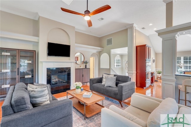 living room featuring ornamental molding, light wood-type flooring, ornate columns, and a high end fireplace