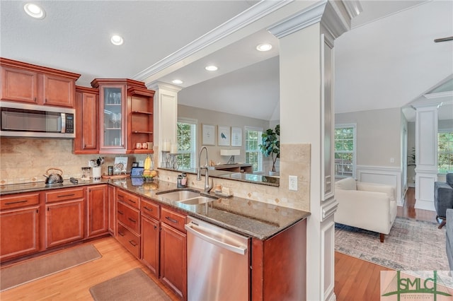 kitchen with appliances with stainless steel finishes, vaulted ceiling, backsplash, light wood-type flooring, and decorative columns