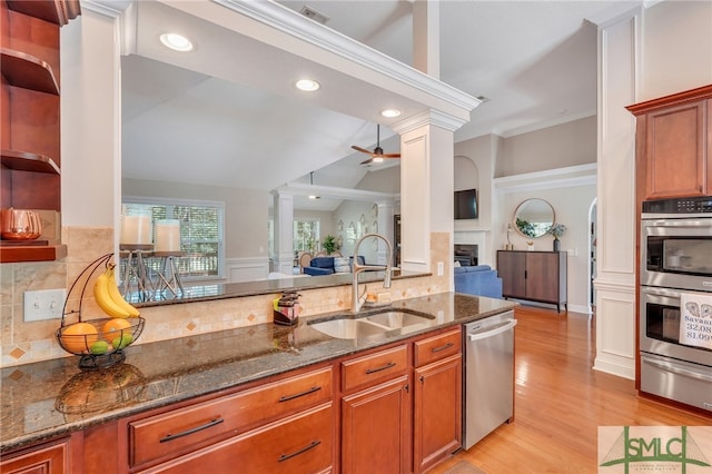 kitchen featuring dark stone counters, light wood-type flooring, tasteful backsplash, sink, and appliances with stainless steel finishes