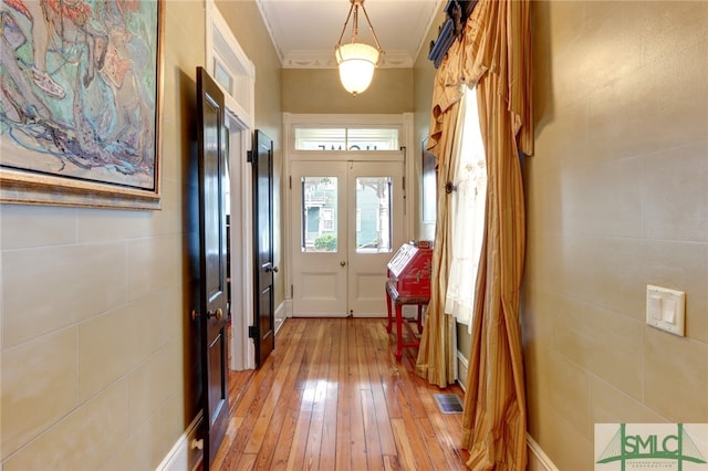 doorway to outside with crown molding, tile walls, french doors, and hardwood / wood-style flooring