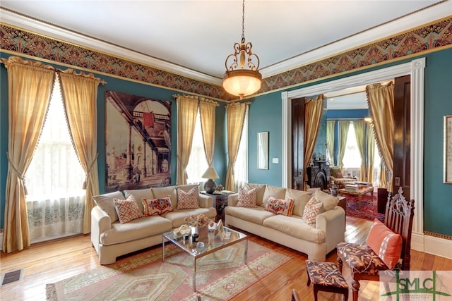 living room with an inviting chandelier, wood-type flooring, plenty of natural light, and ornamental molding