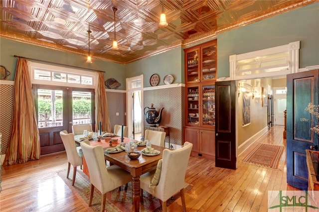 dining room with light hardwood / wood-style floors, french doors, and crown molding