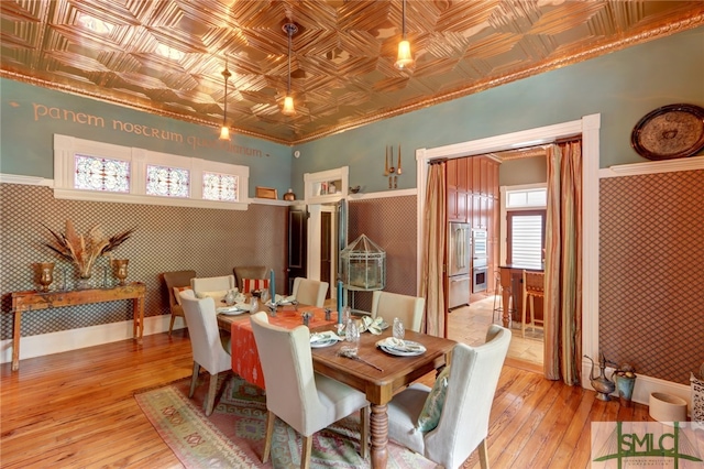 dining room featuring ornamental molding, light wood-type flooring, and a wealth of natural light