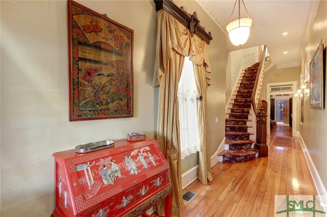 hallway featuring plenty of natural light, hardwood / wood-style floors, and crown molding