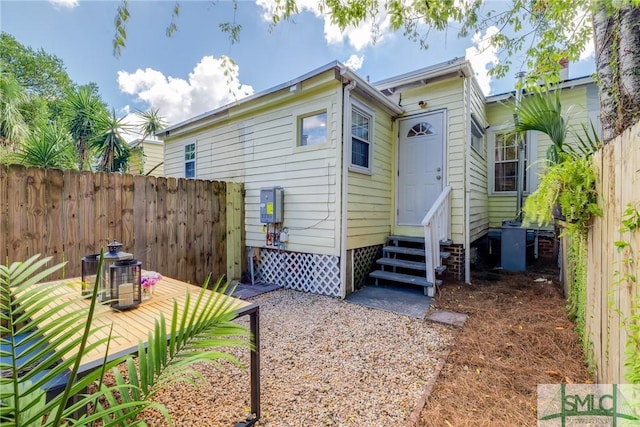 rear view of house featuring entry steps and a fenced backyard