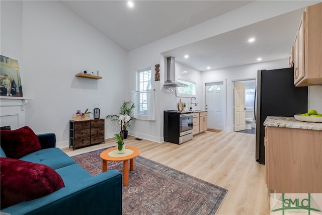 living room with light wood-type flooring, a fireplace, vaulted ceiling, and sink