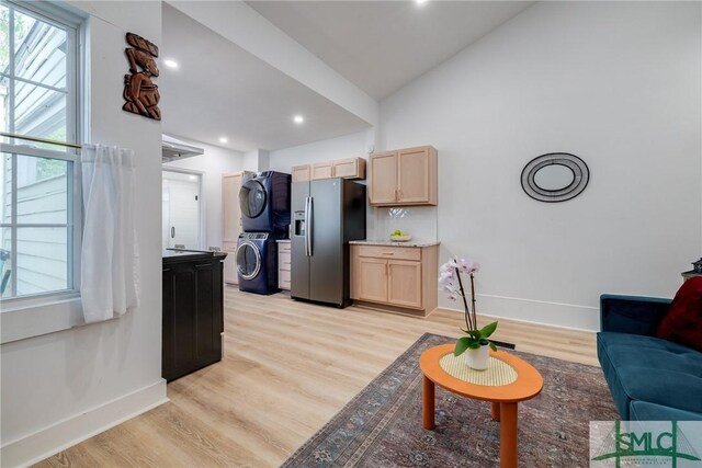 living room with light hardwood / wood-style flooring, lofted ceiling, and stacked washer / drying machine