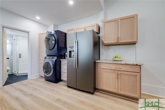 laundry room featuring light hardwood / wood-style floors and stacked washer and dryer